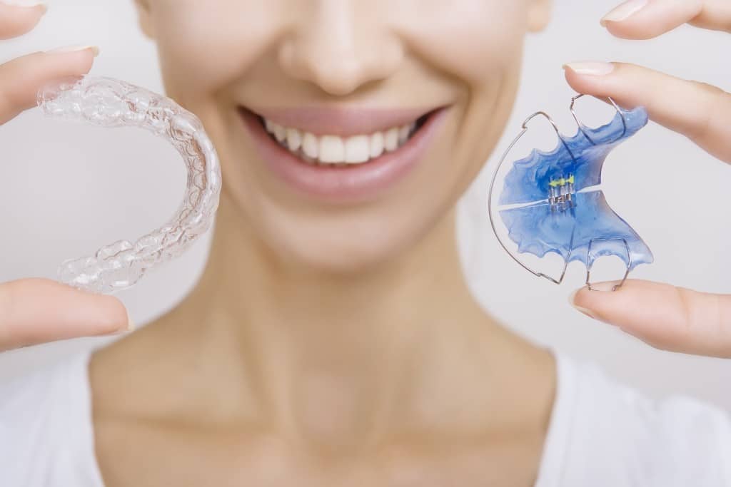 Smiling woman holding two different types of retainers