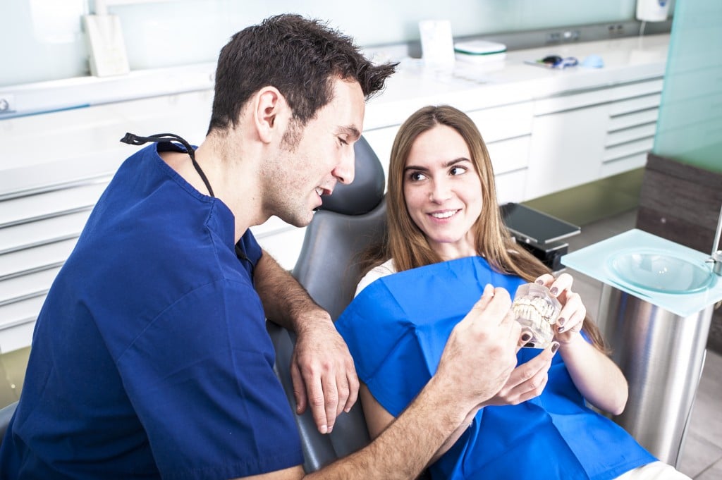Male dentist speaking to female patient